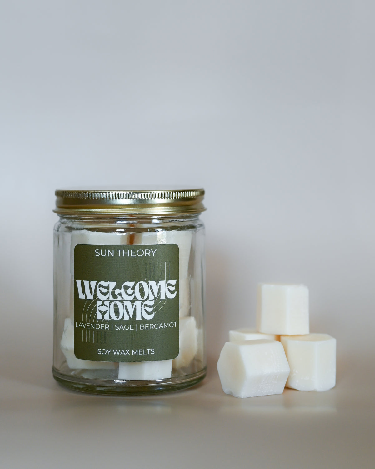Jar of 'Welcome Home' soy wax melts by Sun Theory with wax melts beside it on a light background
