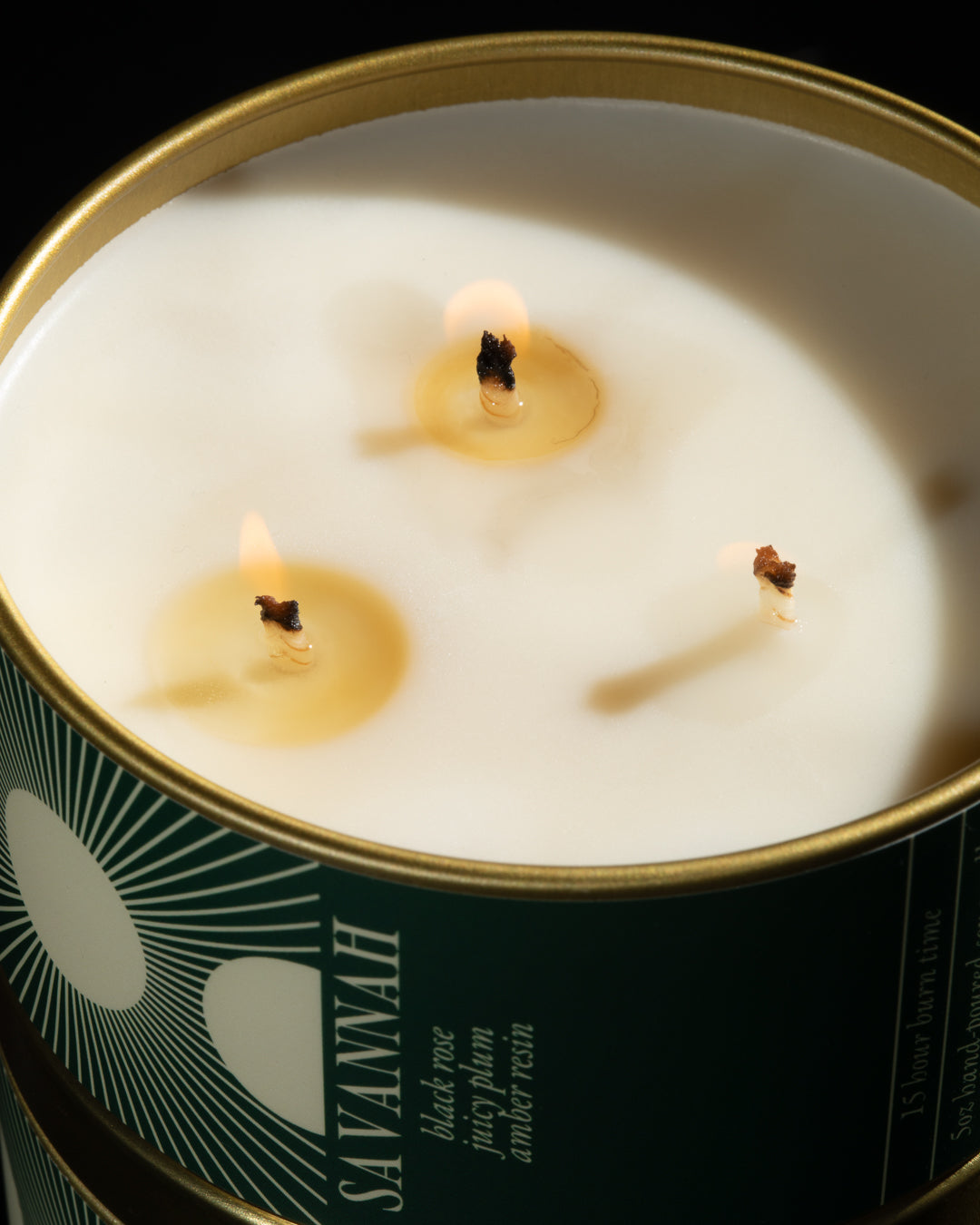 Candle in a tin labeled 'Savannah' with a close-up of the candle's wick.