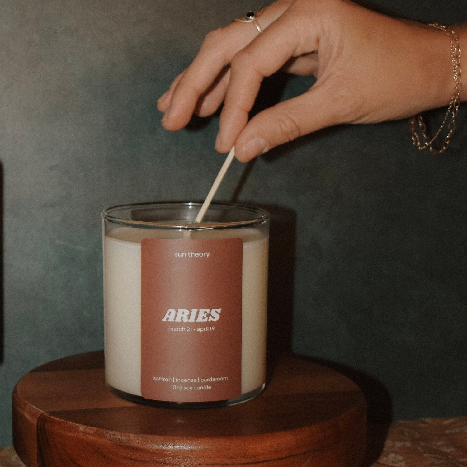 Hand lighting a candle labeled "Aries"