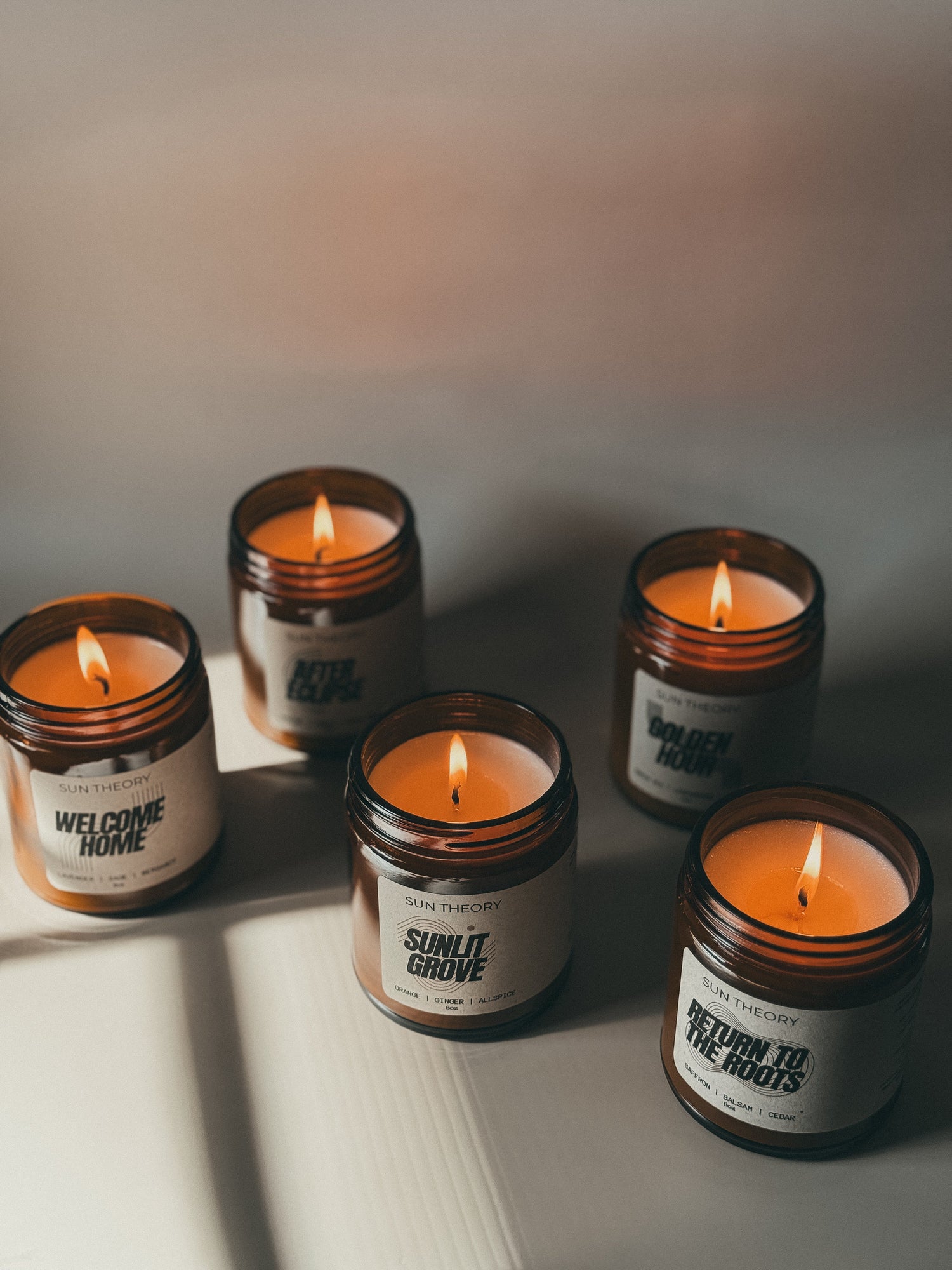 Five Sun Theory branded candles on a white back drop