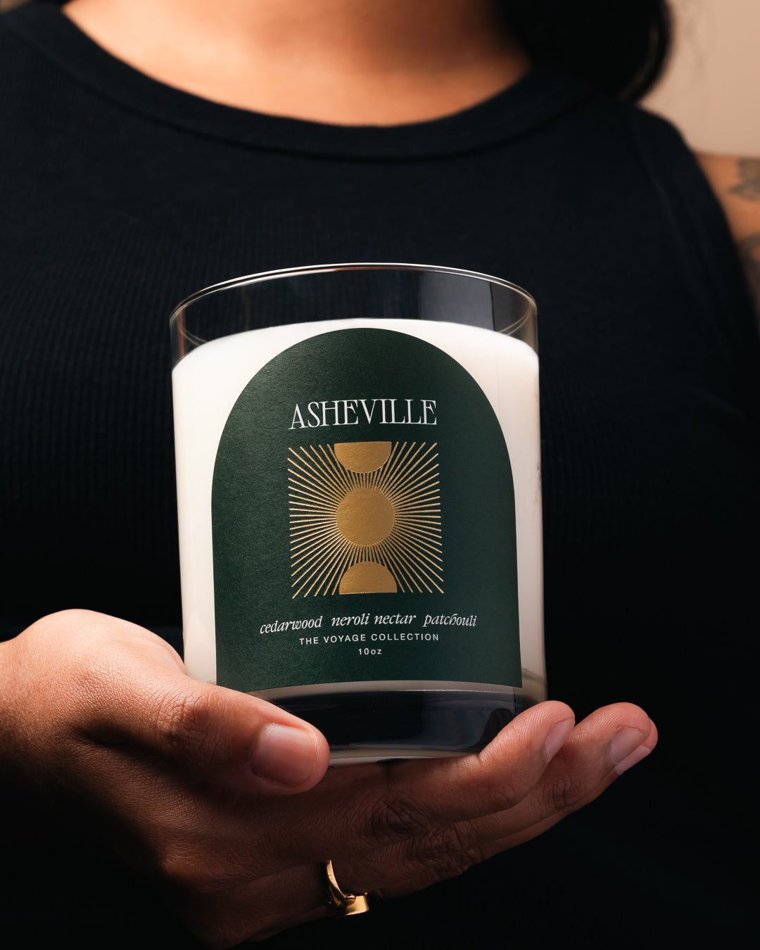 Person holding a candle labeled 'Asheville' with a green label.