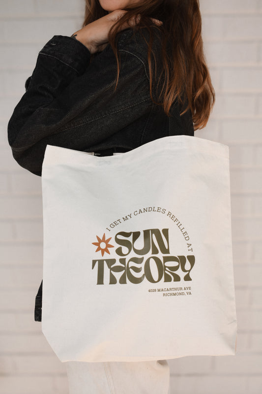 Person holding a tote bag with 'Sun Theory' branding.