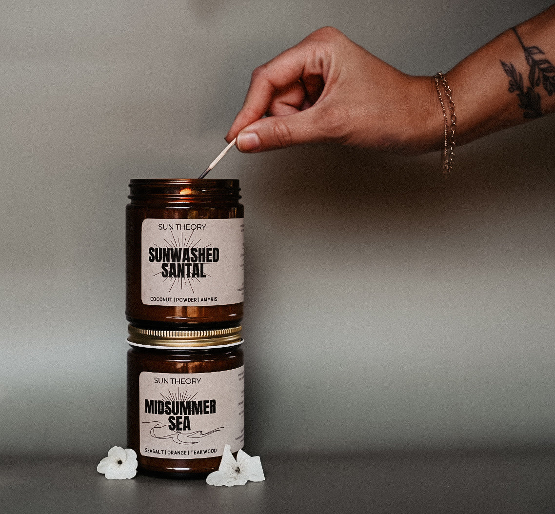 Hand lighting a candle labeled 'Sun Theory' with a neutral background