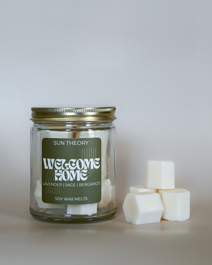 Jar of 'Welcome Home' soy wax melts by Sun Theory with wax melts beside it on a light background