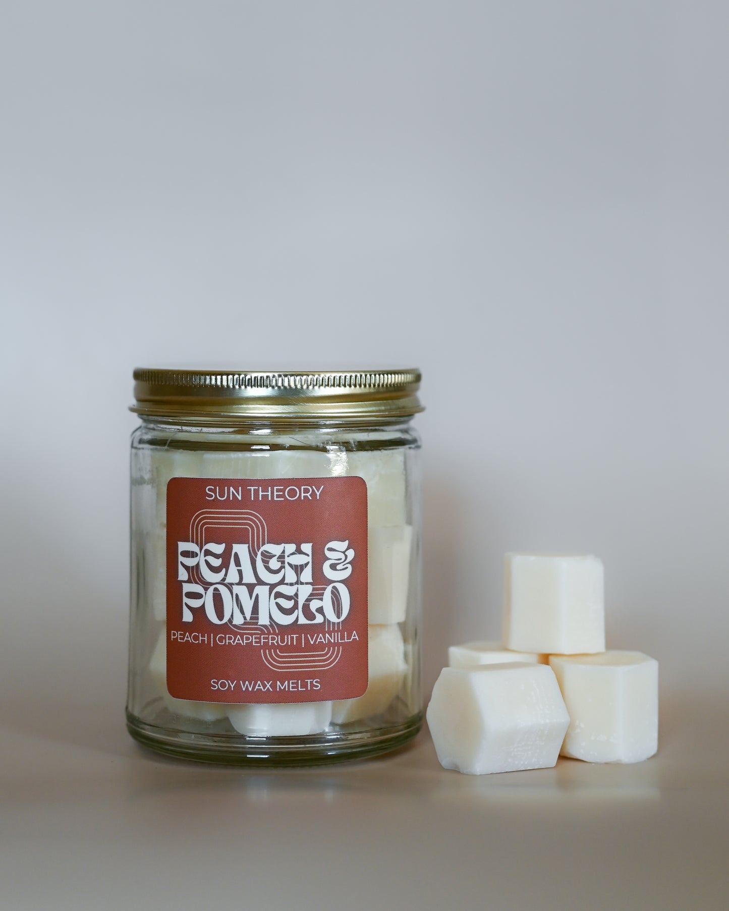 Jar of Sun Theory Peach & Pomelo soy wax melts on a neutral background