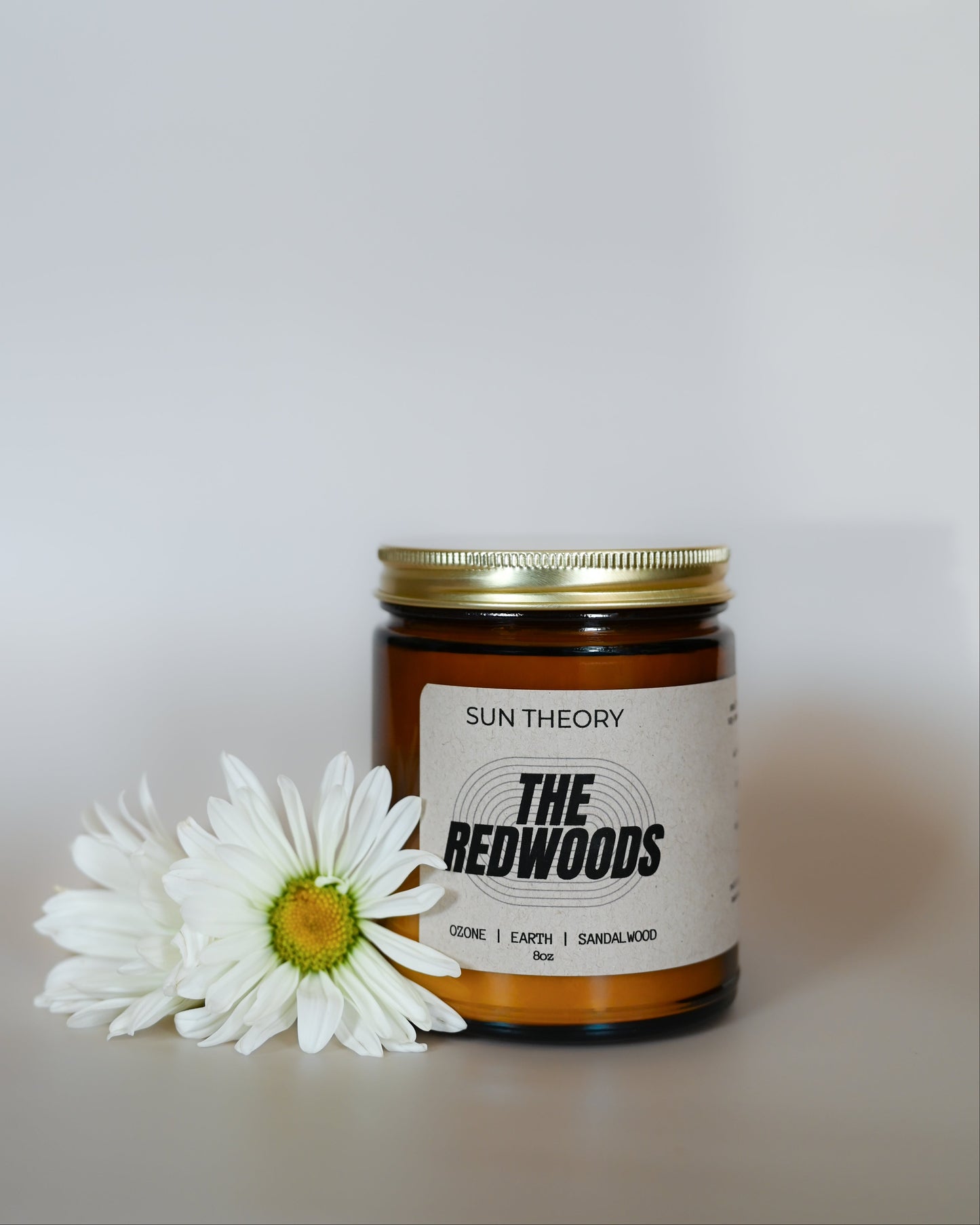 Jar of 'The Redwoods' product by Sun Theory with a white flower on a light background