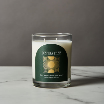 Candle with a green and gold 'Joshua Tree' label on a gray background