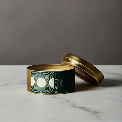 Joshua Tree Candle in a gold tin with a green label on a marble surface