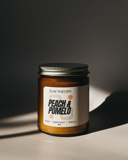 Sun Theory peach and pomelo candle jar on a dark background