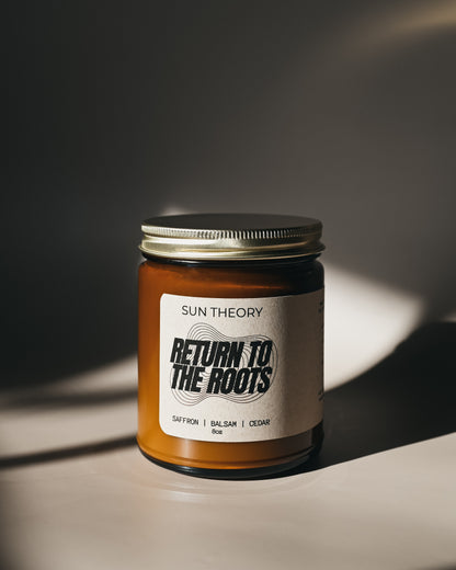 Jar of candle labeled 'Return to the Roots' by Sun Theory on a dark background