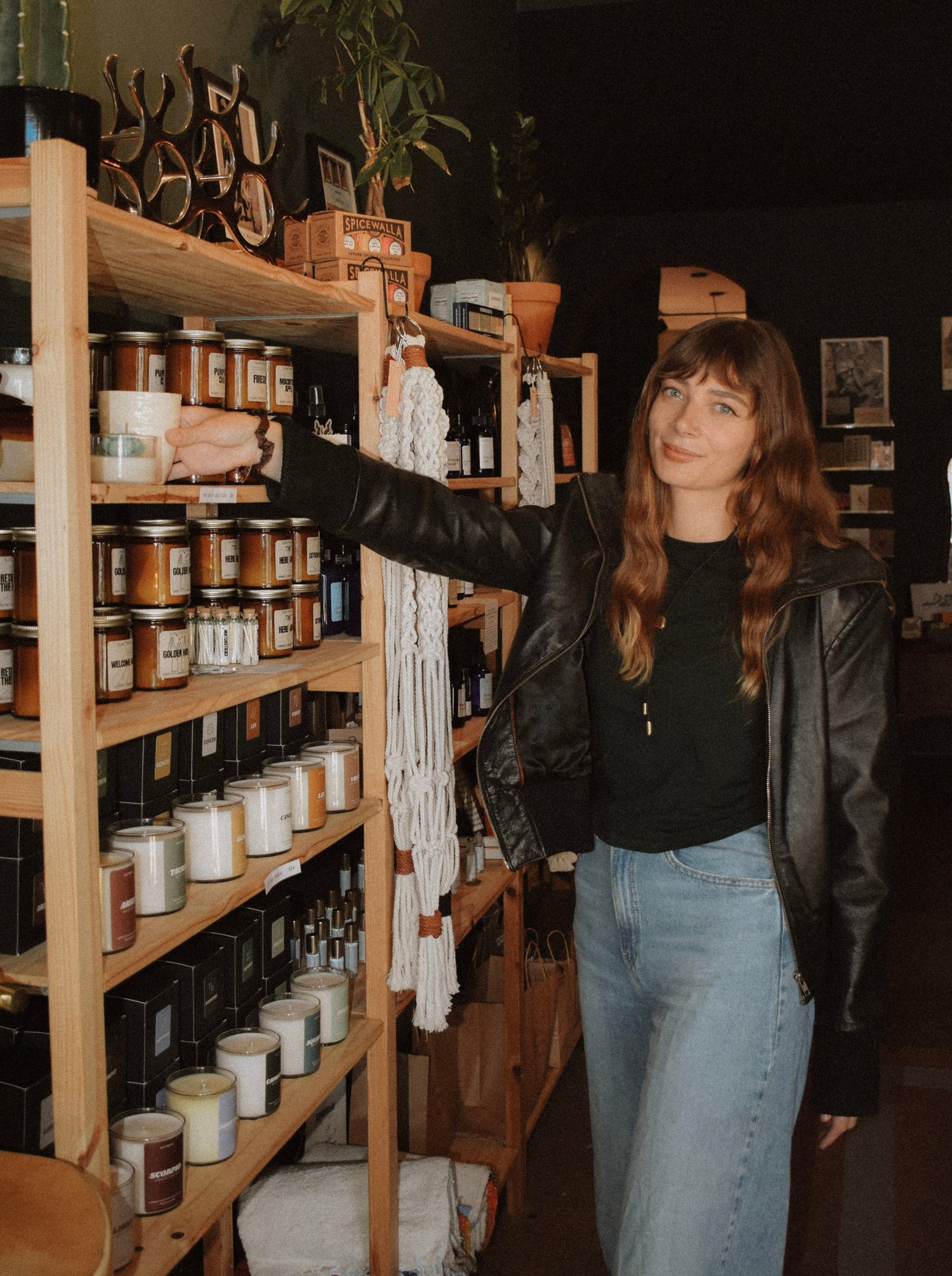 Woman standing in a store with shelves stocked with candles and other products