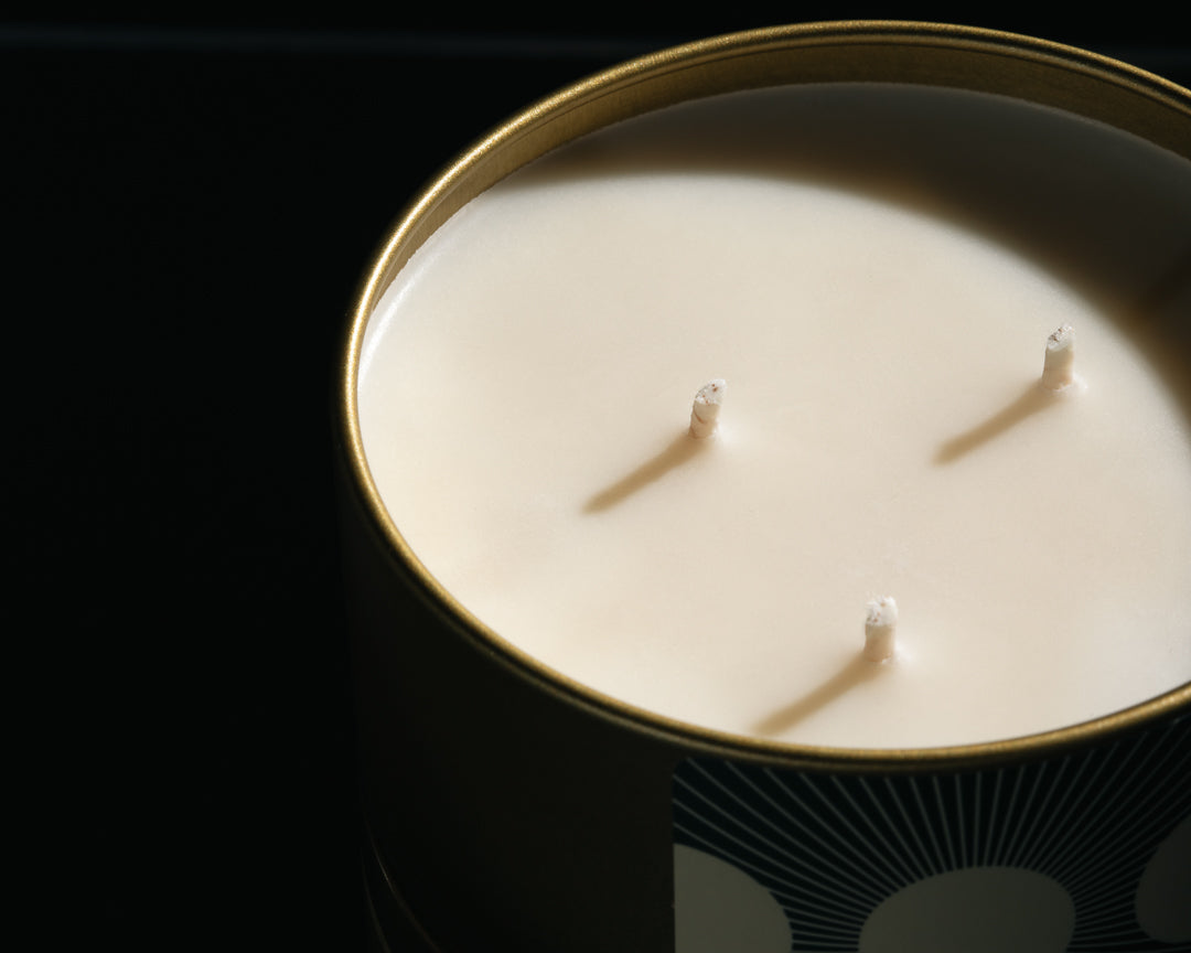 Three-wick candle in a decorative tin with a black background