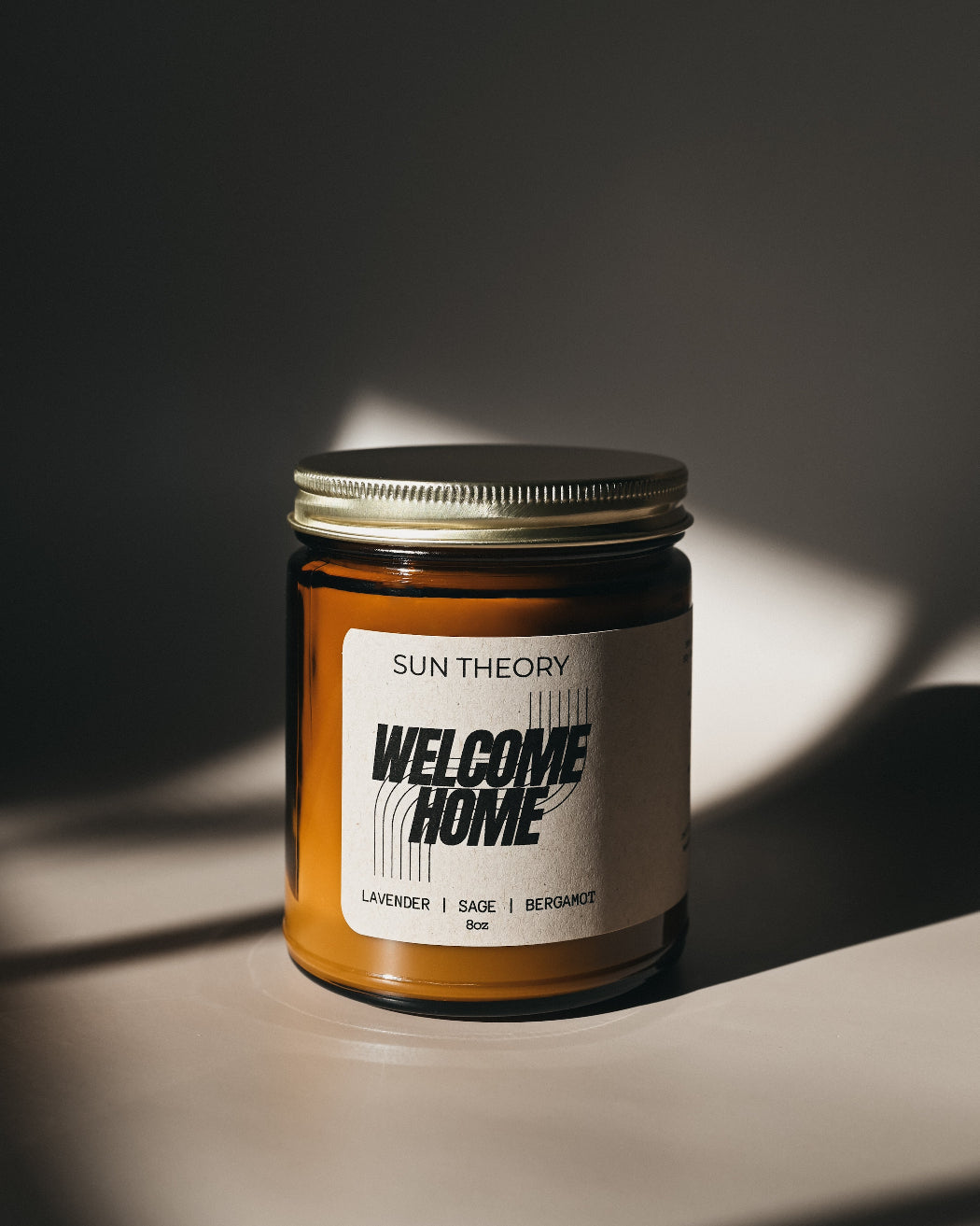 Candle jar labeled 'Sun Theory Welcome Home' on a dark background