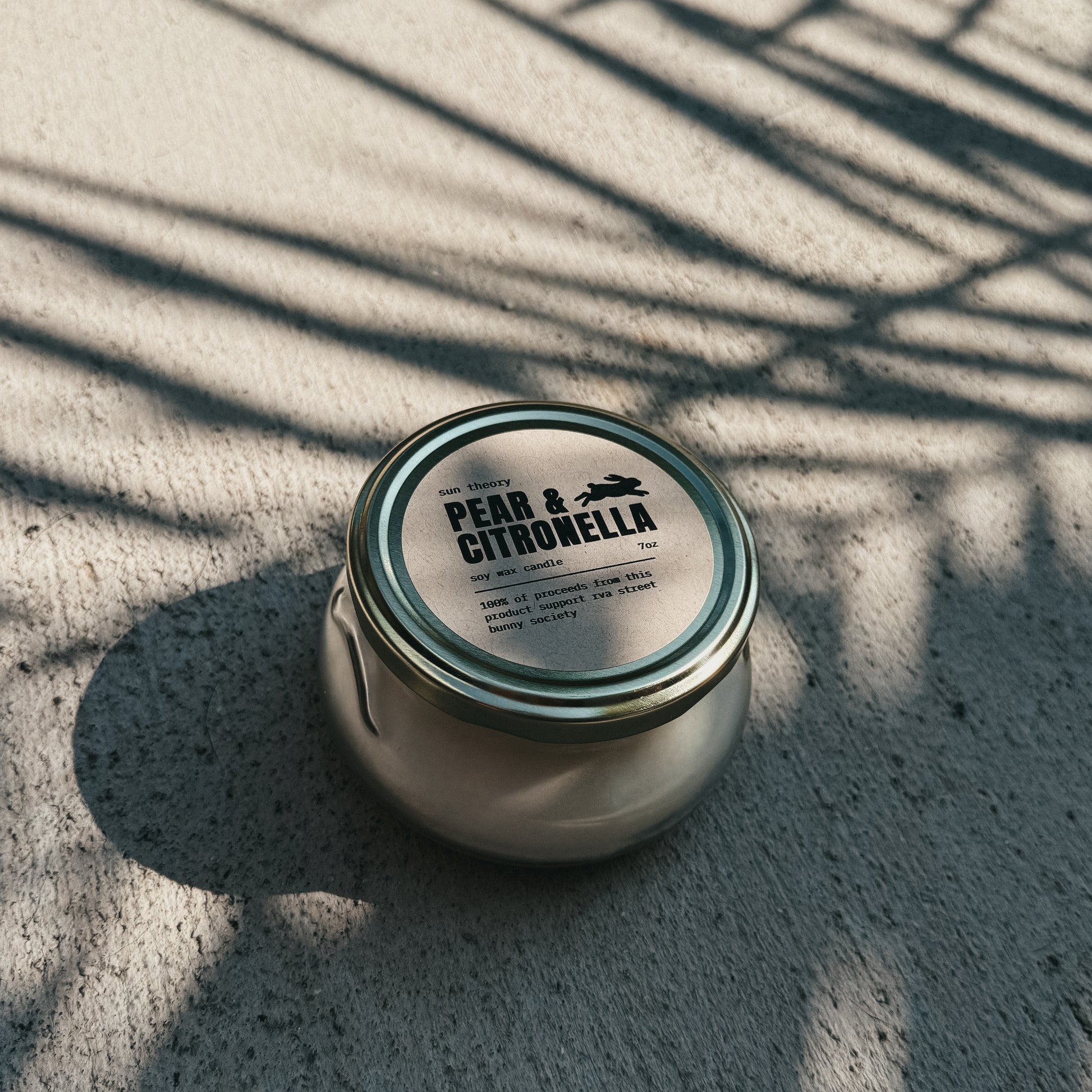 Jar of Pear & Citronella candle on a textured surface with shadows