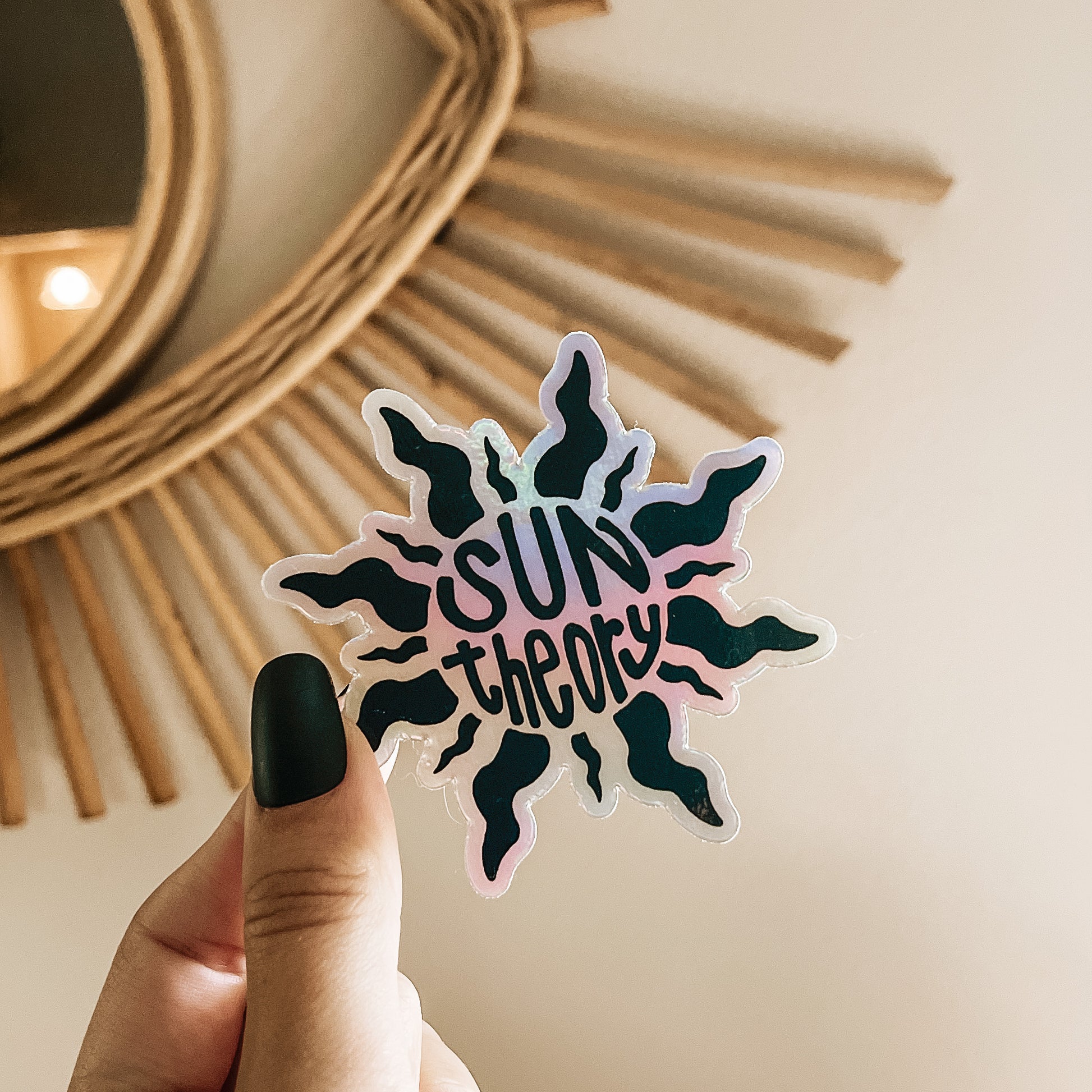 Hand holding a holographic sun theory sticker
