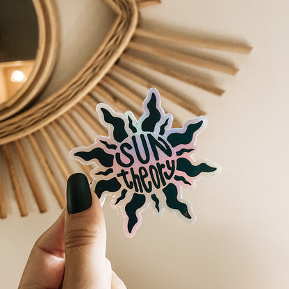 Hand holding a holographic sun theory sticker