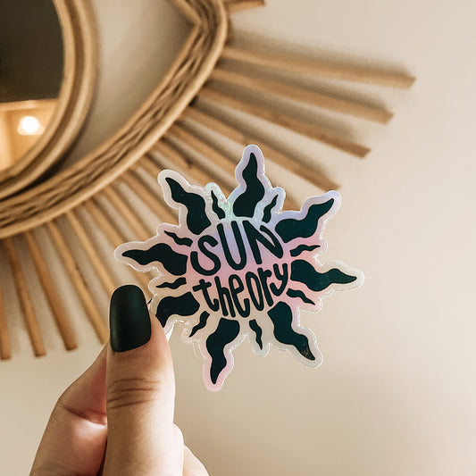 Hand holding a holographic sun theory sticker